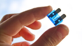 A close up of a man's hand holding a blue fuse
